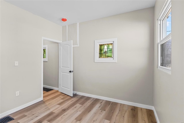 spare room featuring light wood-type flooring, visible vents, and baseboards