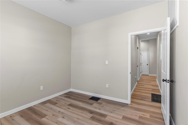 empty room featuring light wood-type flooring, baseboards, and visible vents