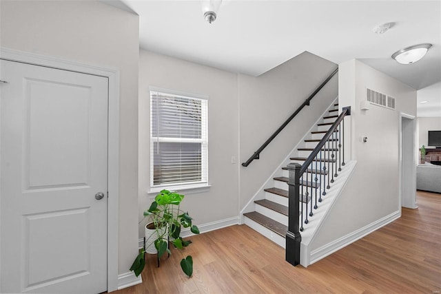 stairway featuring baseboards, visible vents, and wood finished floors