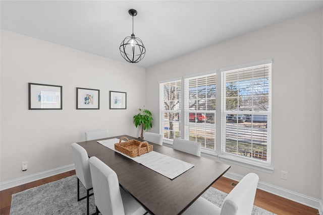 dining room with a notable chandelier, baseboards, and wood finished floors