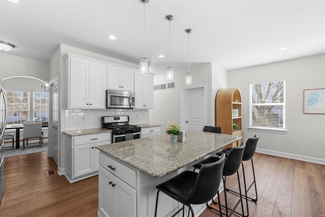 kitchen with white cabinetry, appliances with stainless steel finishes, decorative backsplash, and dark wood finished floors