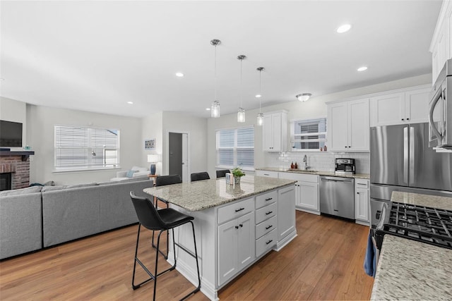 kitchen with open floor plan, stainless steel appliances, a breakfast bar, and a sink