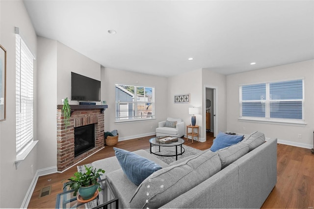 living area with baseboards, visible vents, wood finished floors, a fireplace, and recessed lighting