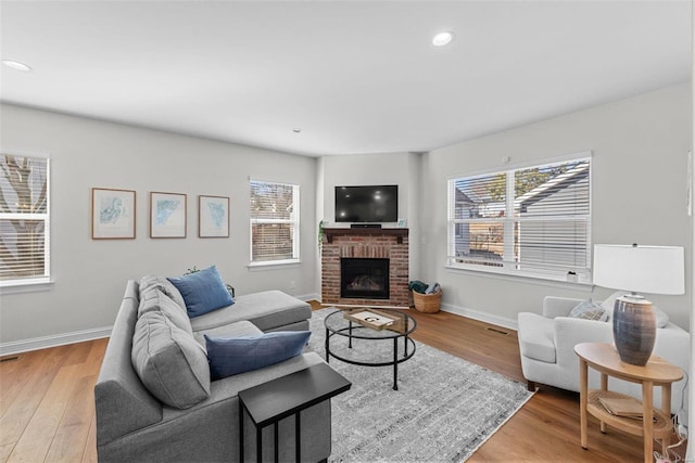 living room with a brick fireplace, light wood-style flooring, baseboards, and recessed lighting