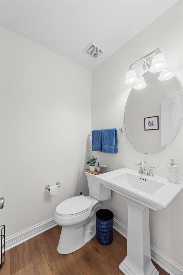 half bathroom featuring baseboards, visible vents, toilet, and wood finished floors