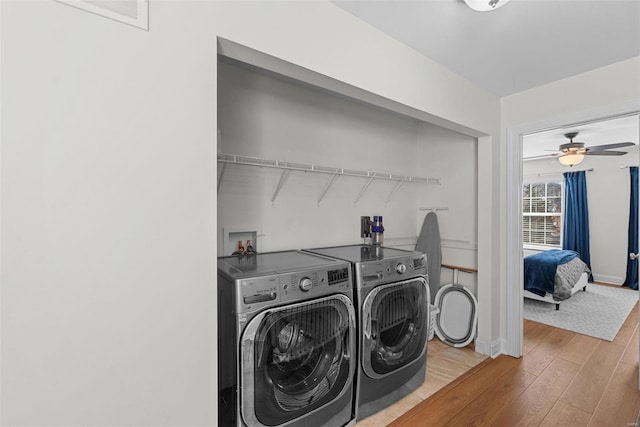 washroom featuring laundry area, wood finished floors, a ceiling fan, baseboards, and washer and dryer