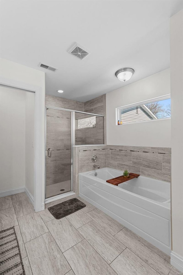 full bathroom featuring a bath, a shower stall, visible vents, and baseboards