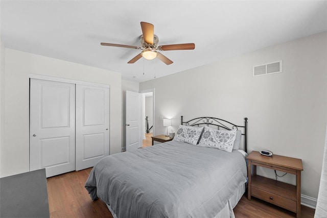 bedroom featuring ceiling fan, a closet, visible vents, and wood finished floors