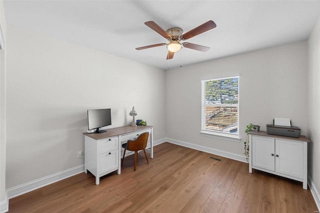 office with light wood-style floors, baseboards, visible vents, and ceiling fan