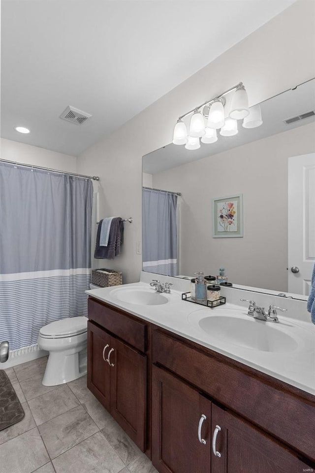 bathroom with toilet, a sink, and visible vents