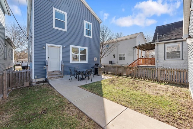 back of property with entry steps, a patio area, a fenced backyard, and a lawn