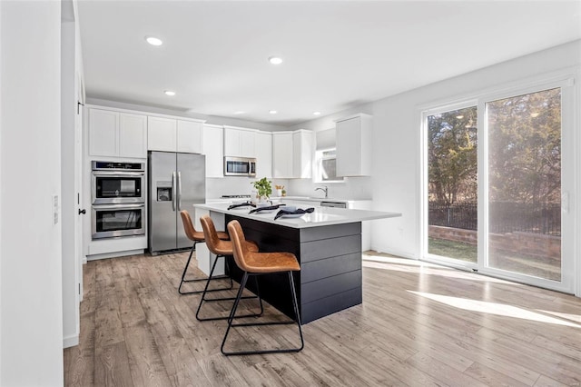 kitchen with stainless steel appliances, white cabinets, light countertops, and light wood-style flooring