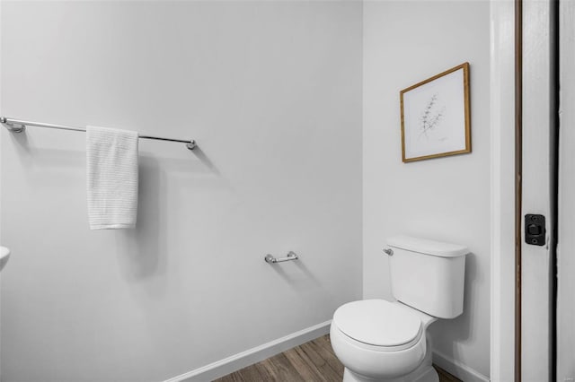 bathroom with toilet, baseboards, and wood finished floors