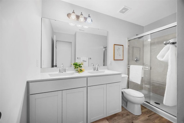 full bathroom featuring a stall shower, visible vents, a sink, and wood finished floors