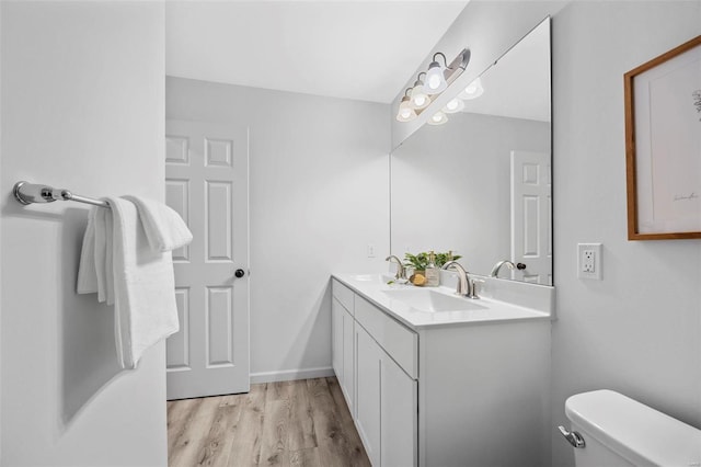 full bathroom featuring double vanity, a sink, toilet, and wood finished floors