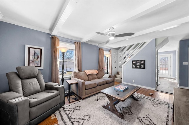 living area with hardwood / wood-style flooring, a ceiling fan, baseboards, stairs, and beam ceiling