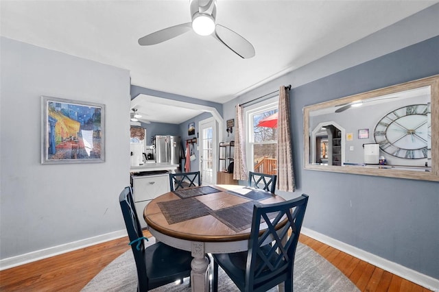 dining space with light wood finished floors, a ceiling fan, and baseboards