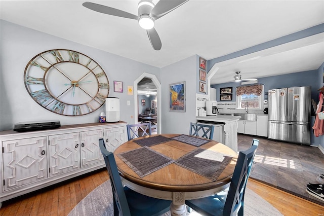 dining room with arched walkways, ceiling fan, and hardwood / wood-style floors