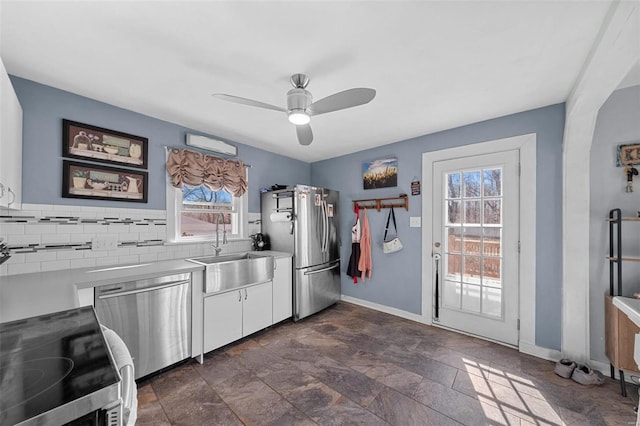 kitchen featuring a sink, baseboards, light countertops, appliances with stainless steel finishes, and tasteful backsplash