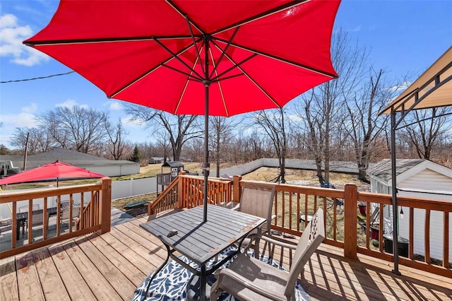 wooden deck featuring a storage shed, outdoor dining space, and a fenced backyard