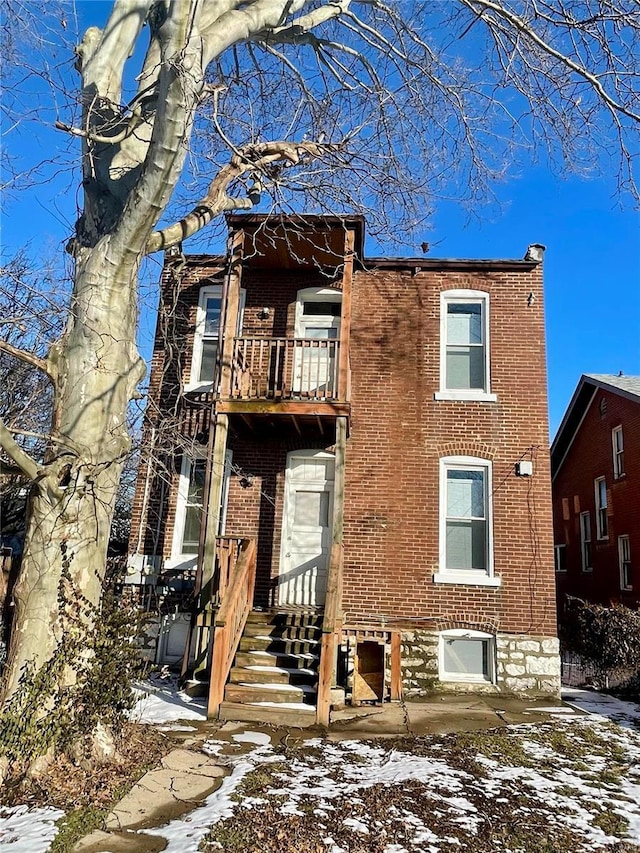 view of front of property featuring brick siding and a balcony