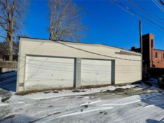 snow covered garage featuring fence