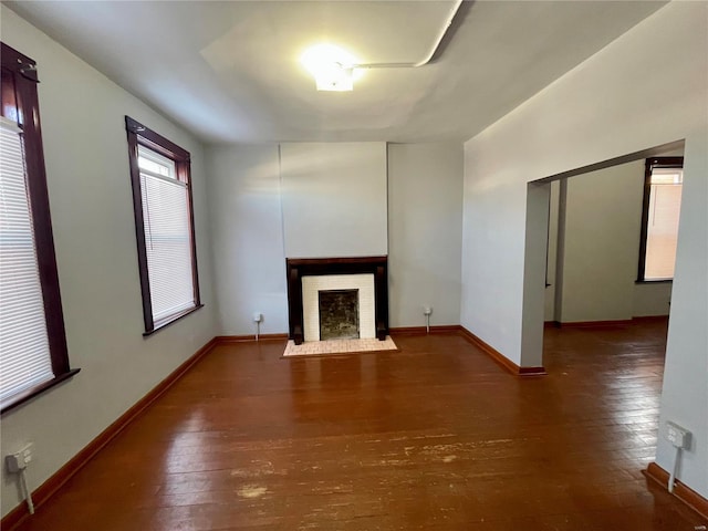 unfurnished living room featuring wood-type flooring, a fireplace, and baseboards