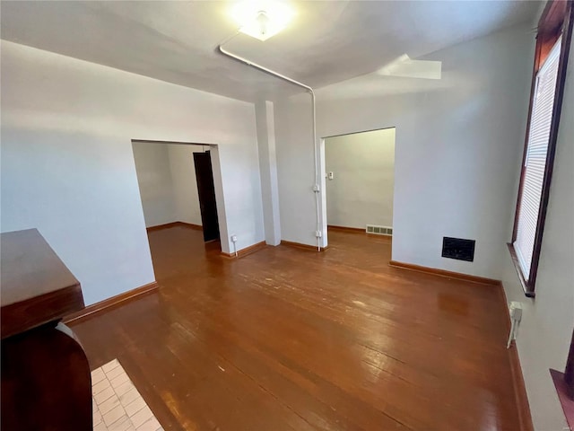 empty room with visible vents, baseboards, and wood finished floors