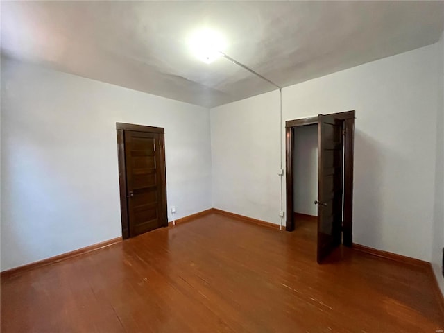 spare room with baseboards and wood finished floors