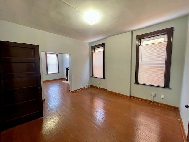 unfurnished bedroom with wood-type flooring, visible vents, and baseboards