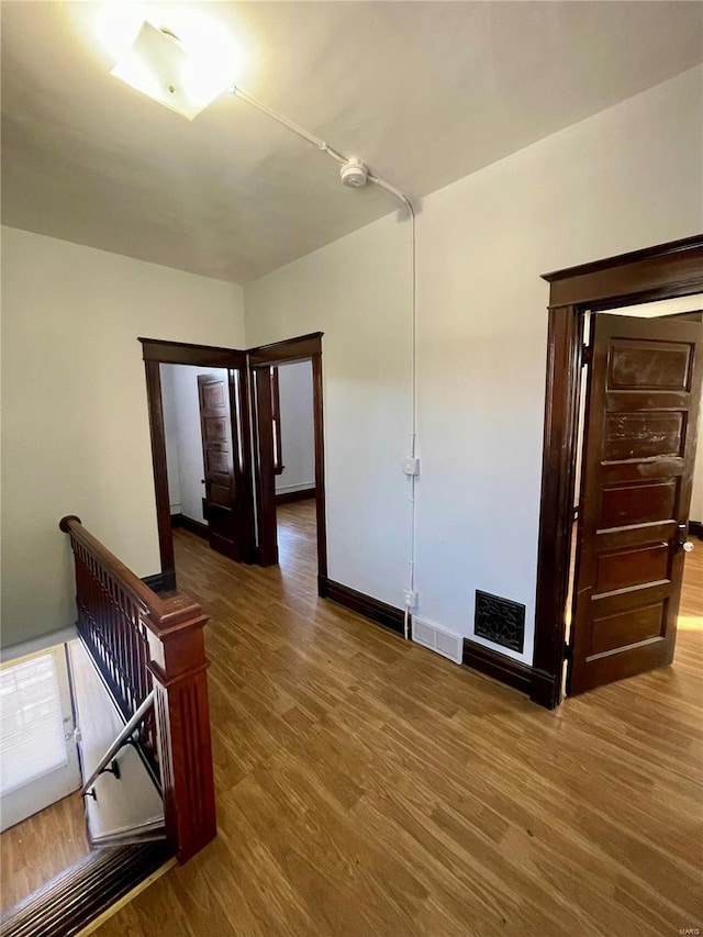 interior space with wood finished floors, an upstairs landing, and visible vents