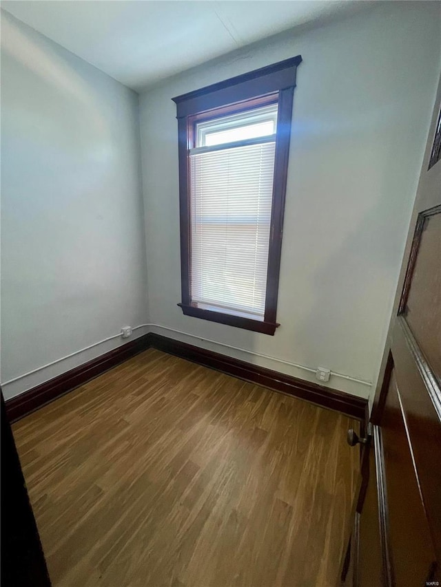 empty room featuring baseboards and dark wood finished floors