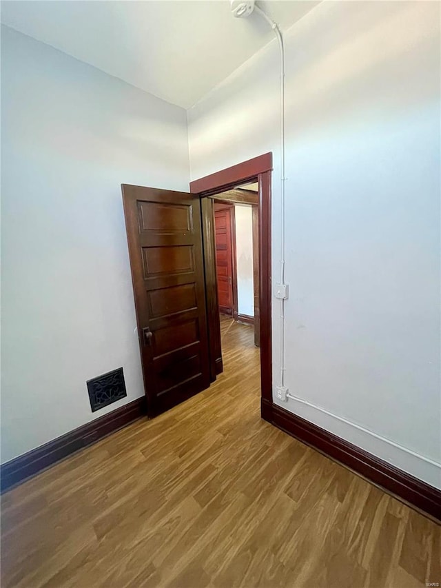 spare room featuring wood finished floors, visible vents, and baseboards