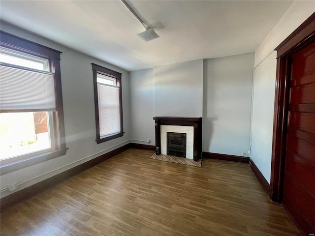 unfurnished living room featuring a fireplace, baseboards, and wood finished floors