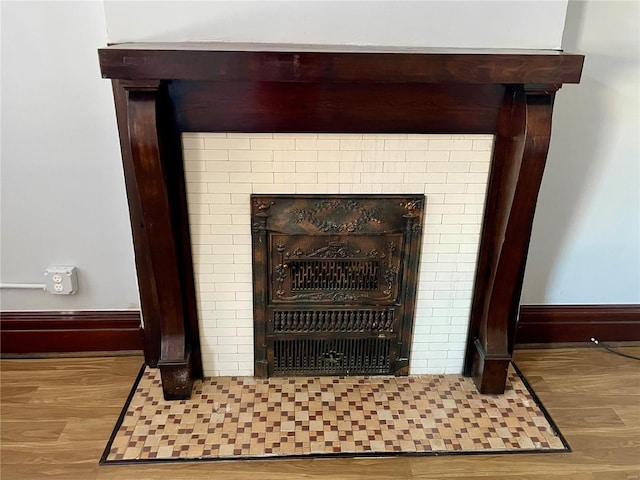 room details featuring a fireplace, wood finished floors, and baseboards