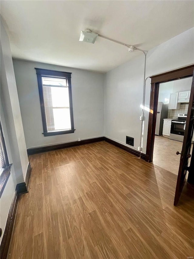 empty room featuring wood finished floors, visible vents, and baseboards