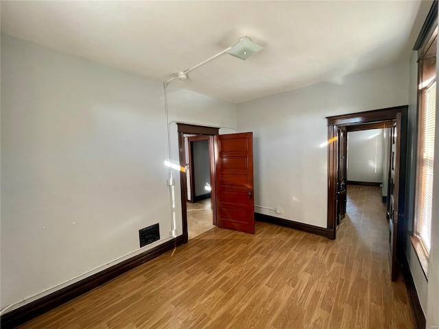 unfurnished bedroom with visible vents, baseboards, and wood finished floors