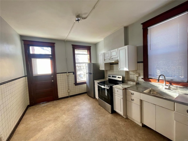 kitchen featuring appliances with stainless steel finishes, stainless steel counters, wainscoting, and a sink