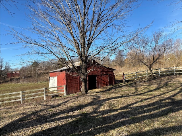 view of pole building featuring a rural view, fence, and a lawn