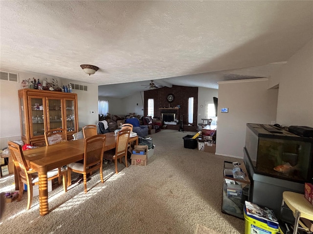 dining area with lofted ceiling, carpet, a fireplace, and visible vents