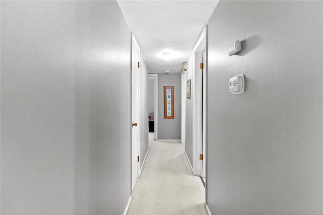 hallway featuring baseboards and light colored carpet