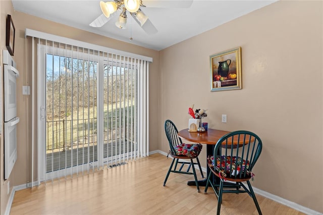 dining room with a ceiling fan, baseboards, and wood finished floors