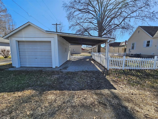 garage with a carport, fence, and driveway