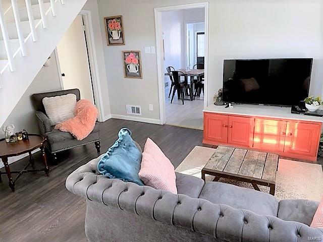 living area with visible vents, dark wood finished floors, baseboards, and stairs