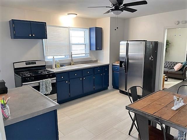 kitchen featuring stainless steel appliances, blue cabinetry, and a sink