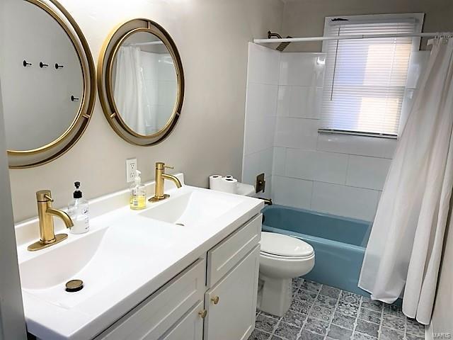 full bathroom featuring shower / tub combo with curtain, a sink, toilet, and double vanity