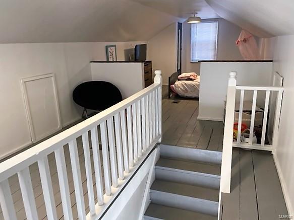 stairway with vaulted ceiling and wood finished floors