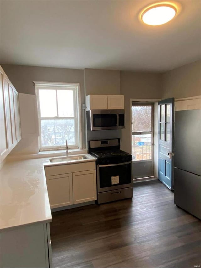 kitchen with stainless steel appliances, dark wood-style flooring, light countertops, and a sink