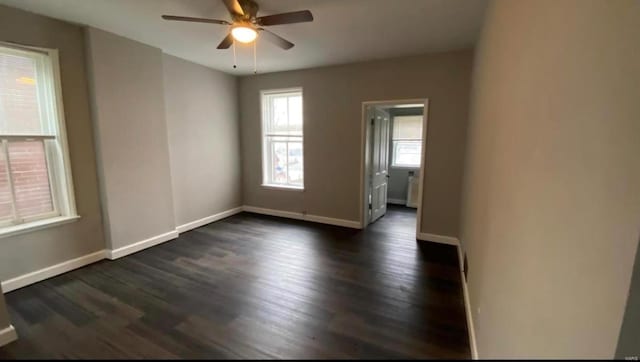 unfurnished room featuring dark wood-style floors, ceiling fan, and baseboards