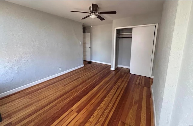 unfurnished bedroom featuring baseboards, a ceiling fan, a textured wall, wood finished floors, and a closet